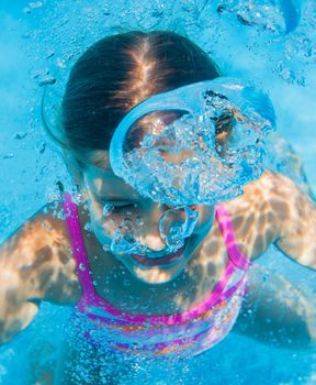 The cute girl swimming underwater and smiling