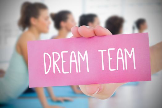 Woman holding pink card saying dream team against fitness class in gym