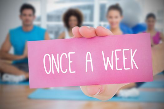 Woman holding pink card saying once a week against fitness class in gym