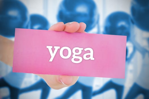 Woman holding pink card saying yoga against fitness class in gym