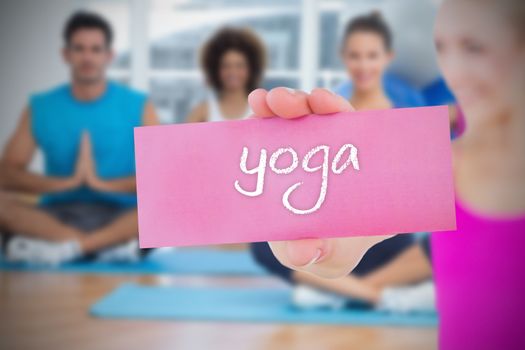 Fit blonde holding card saying yoga against yoga class in gym 