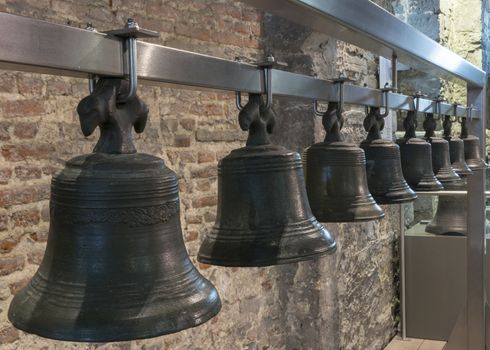 Collection of historic bells hang in Ghent Belfry, Belgium, form a line.