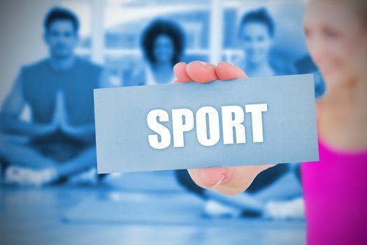 Fit blonde holding card saying sport against yoga class in gym 