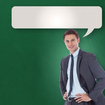 Smiling businessman with hands on hips against speech bubble