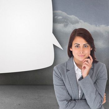 Smiling thoughtful businesswoman with speech bubble against clouds in a room