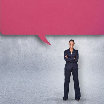 Confident businesswoman with speech bubble against grey wall