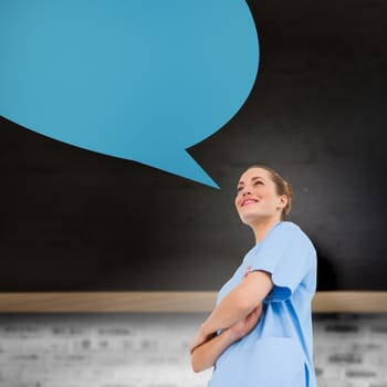 Pretty surgeon with arms crossed with speech bubble against blackboard on wall