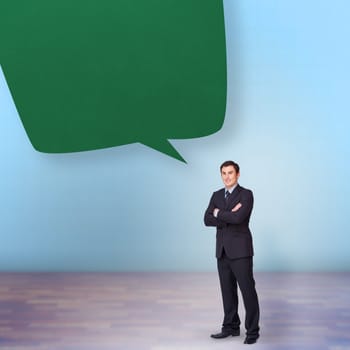 Young businessman standing cross-armed against speech bubble