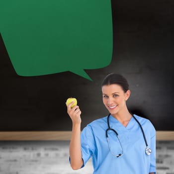 Happy surgeon holding an apple with speech bubble against blackboard on wall