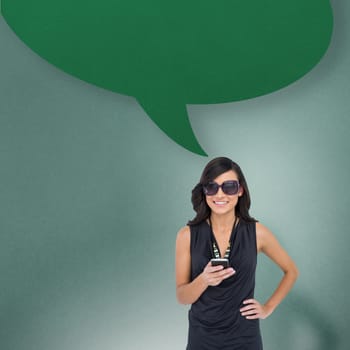 Happy brunette holding smartphone with speech bubble against blue background with vignette
