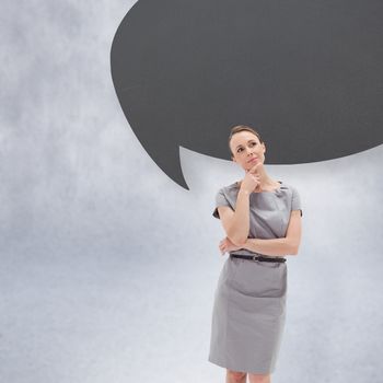 Thoughtful woman posing in dress with speech bubble against grey wall