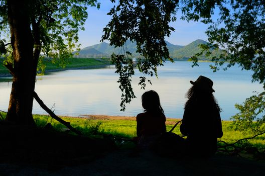 Silhouette two sister sit and relax with reservoir view, Chonburi, Thailand