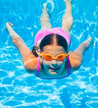 The cute girl swimming underwater and smiling