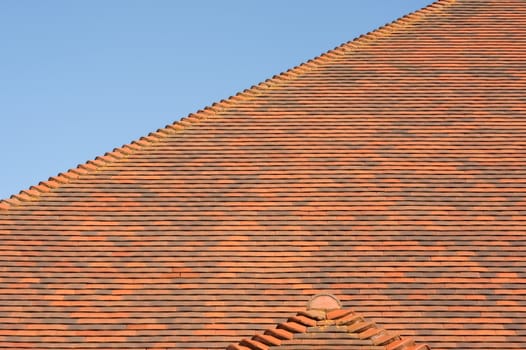 red tiled roof abstract with a blue sky background