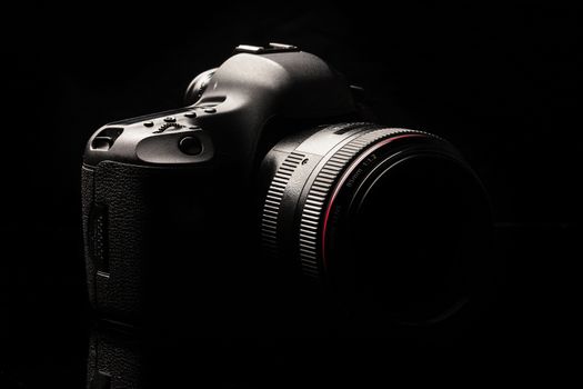 Professional modern DSLR camera low key image - Modern DSLR camera with a very wide aperture lens on