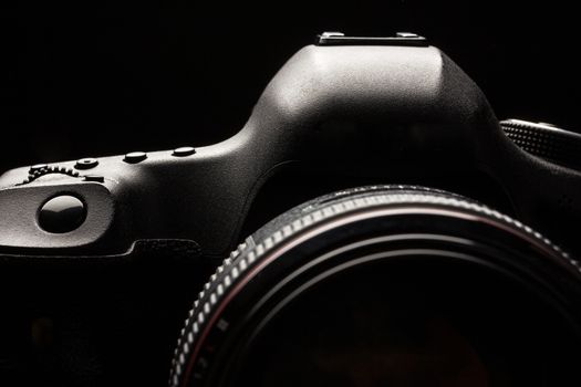 Professional modern DSLR camera low key image - Modern DSLR camera with a very wide aperture lens on