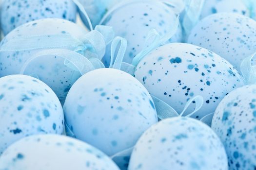 Pale blue speckled painted Easter eggs with ribbons
