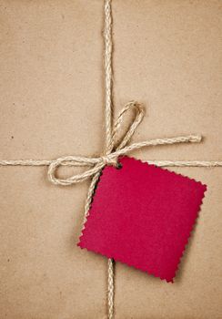 Gift package and red card in brown paper wrapper tied with string close up