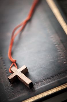 Closeup of simple wooden Christian cross necklace on holy Bible with copy space