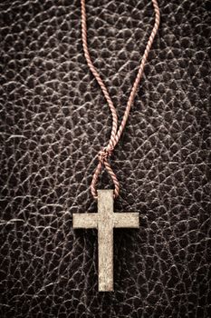 Closeup of simple wooden Christian cross necklace on leather bound holy Bible