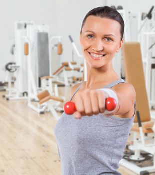beautiful sportswoman with small dumbbell in the gym