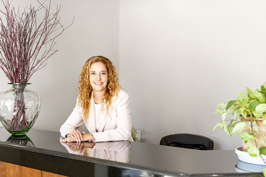 Receptionist standing at reception counter in office