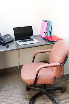 Workstation in office with swivel chair desk and laptop computer
