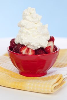 Fresh strawberries with whipped cream in red bowl