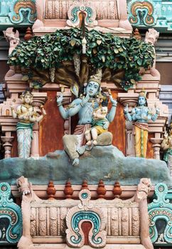 Murugan, Shiva's son, sitting on his knee, statue on the gopuram of Rathinagiri Hill Temple in Vellore, Tamil Nadu, India. 
