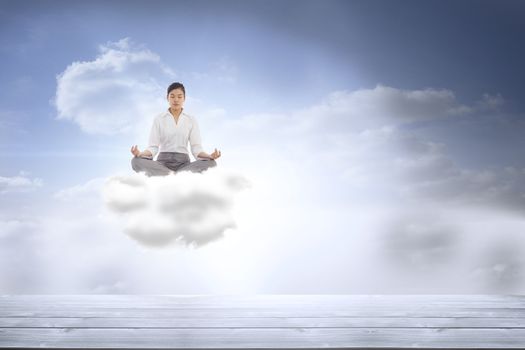 Businesswoman sitting in lotus pose against beautiful blue sky with clouds