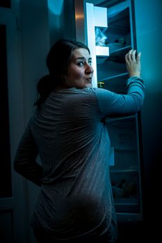 Photo at night of woman opening refrigerator