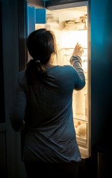 Portrait of hungry woman looking in fridge at late night