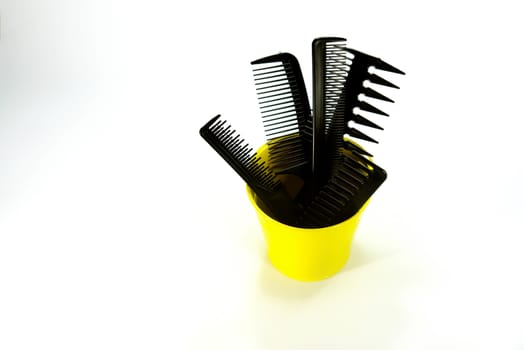 set of plastic combs in yellow bucket on white scene,shallow focus