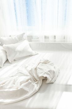 Photo of unmade bed against window