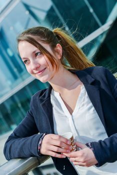 Junior executive having a coffee break in front of her company