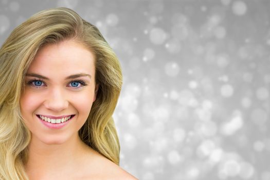 Smiling blonde natural beauty against grey abstract light spot design