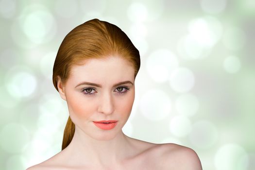 Beautiful redhead looking at camera against grey abstract light spot design