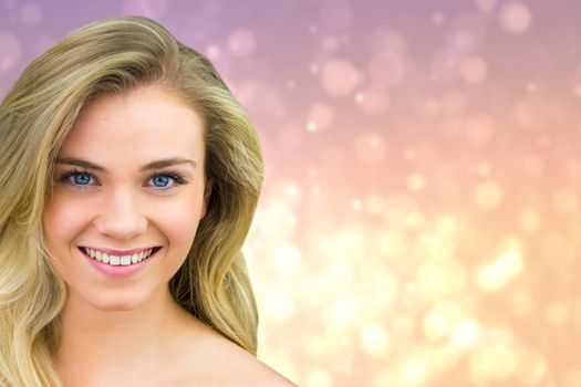 Smiling blonde natural beauty against pink abstract light spot design