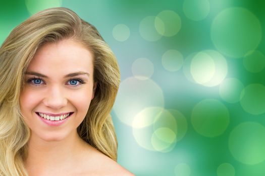 Smiling blonde natural beauty against green abstract light spot design