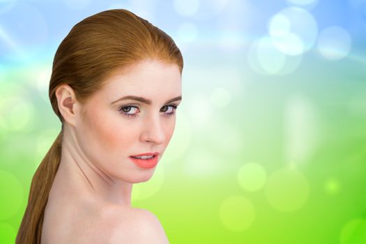 Beautiful redhead looking at camera against green and blue abstract design