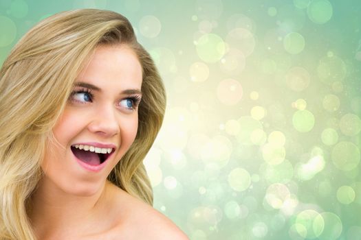 Smiling blonde natural beauty against green abstract light spot design