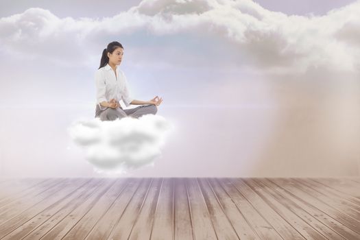 Businesswoman sitting in lotus pose against clouds in a room