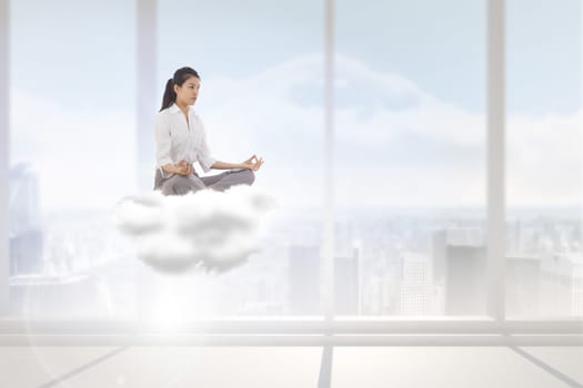 Businesswoman sitting in lotus pose against bright white room with windows