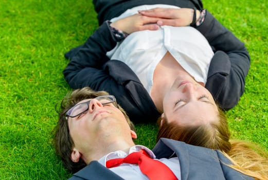 Successful Junior executives dynamics lying on grass