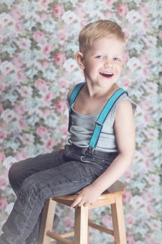 Portrait of funny little boy laughing. Background: floral, soft, pastel