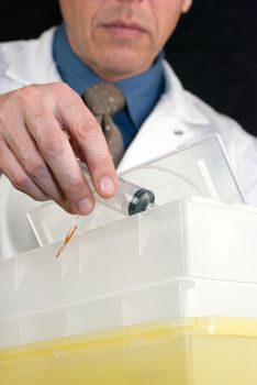 Close-up of a Doctor dropping a syringe with butterfly needle attached into sharps container.