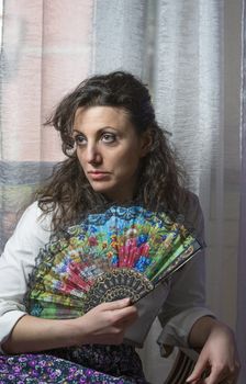 young woman hiding her face behind a fan colored