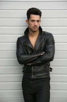 Attractive young man with leather jacket on naked torso, looking at camera