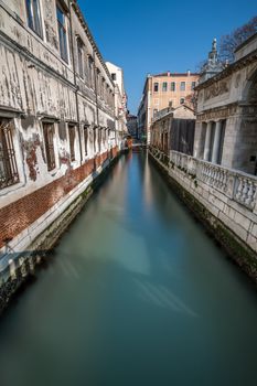 Narrow Canal Among Old Colorful Brick Houses in Venice, Italy