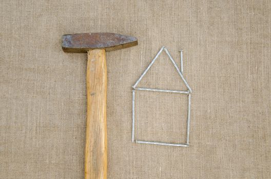 rusty hammer and shape of house made of nail, building new home concept